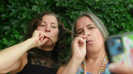 Two women blowing air through straws