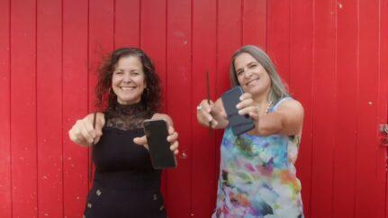 Two women holding straws and cell phones