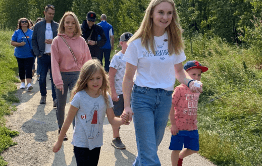 Abbie Clarke holding hands with young children walking in the Clarke Walk for PF