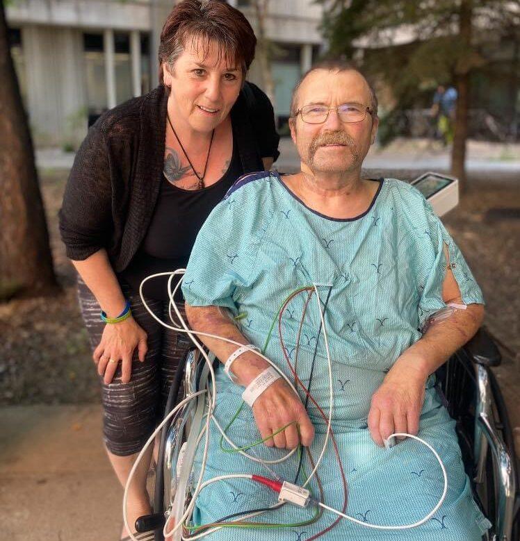 Dale Smith sitting in a wheel chair with his wife behind him post lung transplant surgery