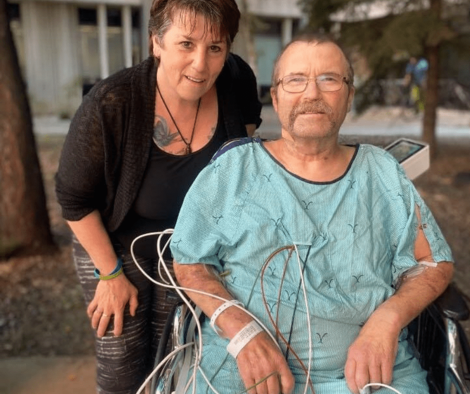 Dale Smith in wheelchair with his wife standing behind him post lung transplant