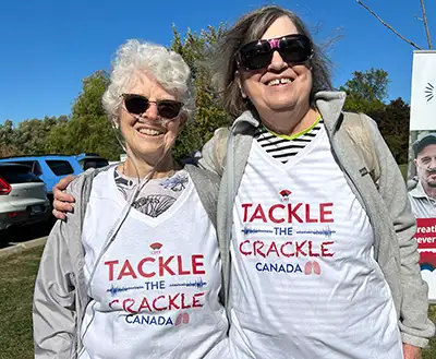 Two women wearing "tackle the crackle" t-shirts at a walk for pulmonary fibrosis awareness. 