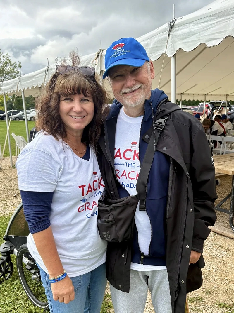 A pulmonary fibrosis patient stands with their caregiver at a walk for pulmonary fibrosis.
